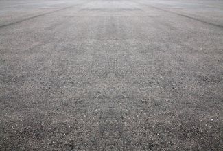 Close-up of a gray asphalt road surface with a rough, textured pattern.