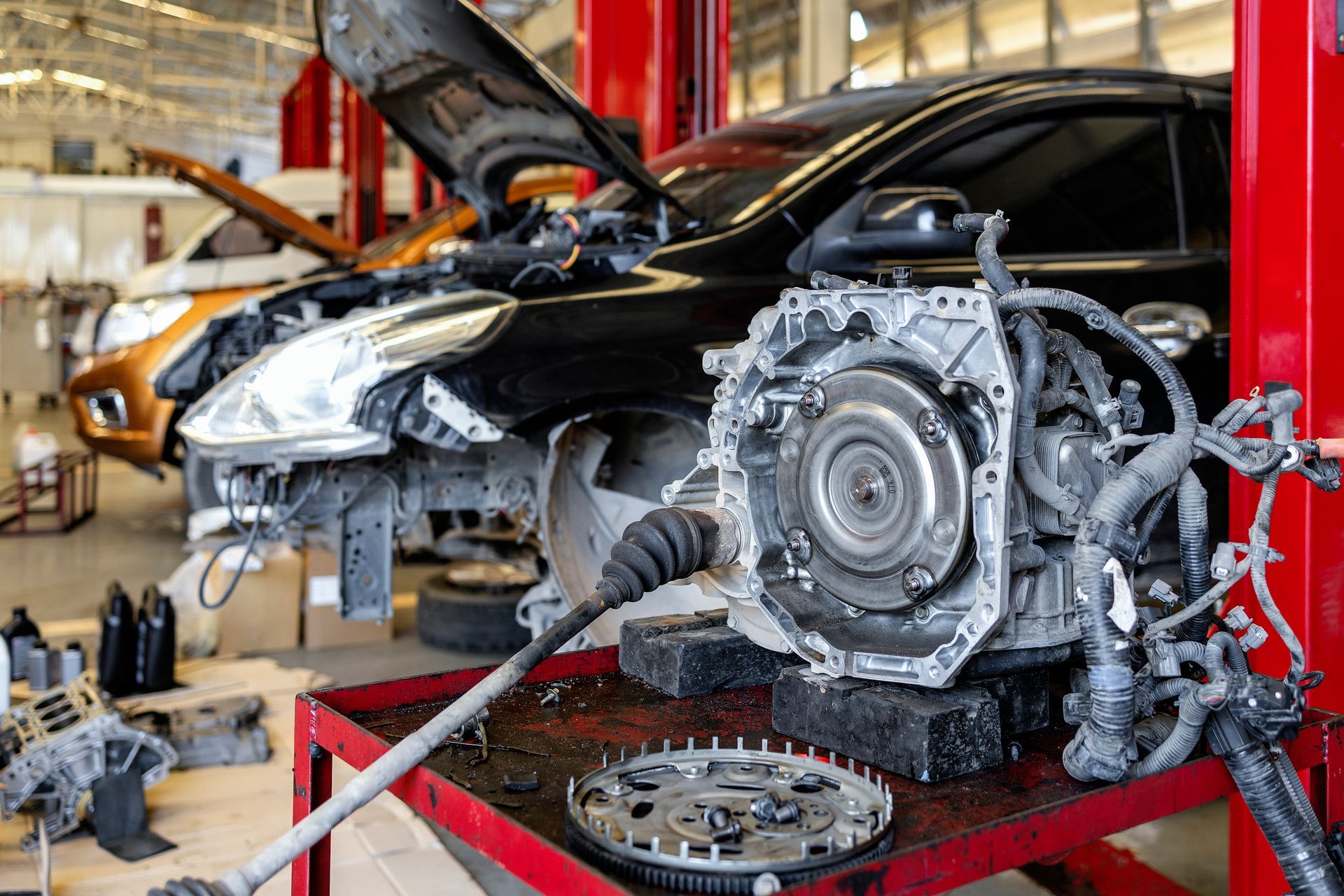 Automatic transmission system disassembled on a workbench in a professional auto repair shop.