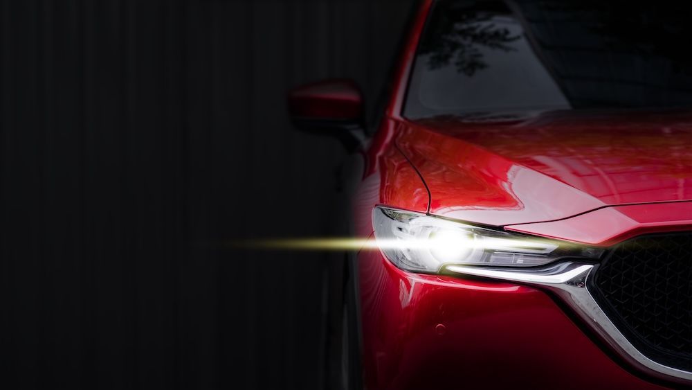 A close up of a red Mazda car 's headlight in the dark — Marx Forster Tyres & Mechanical In Forster, NSW