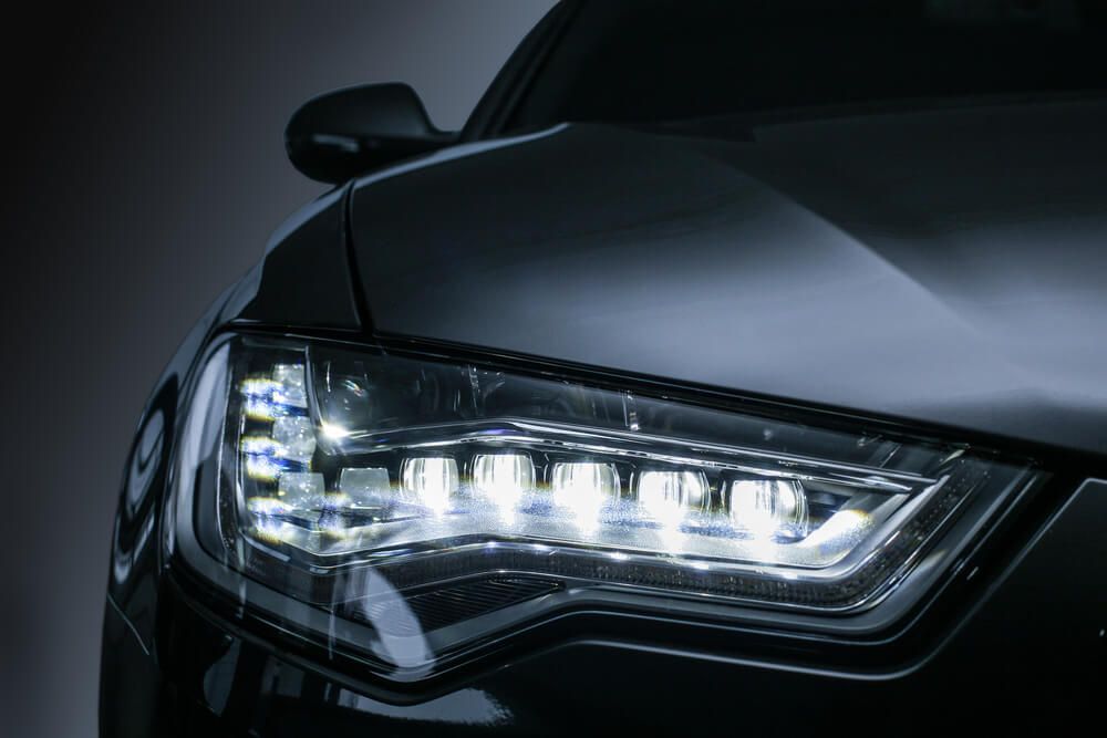 A close up of a car 's headlights on a dark background — Marx Forster Tyres & Mechanical In Forster, NSW