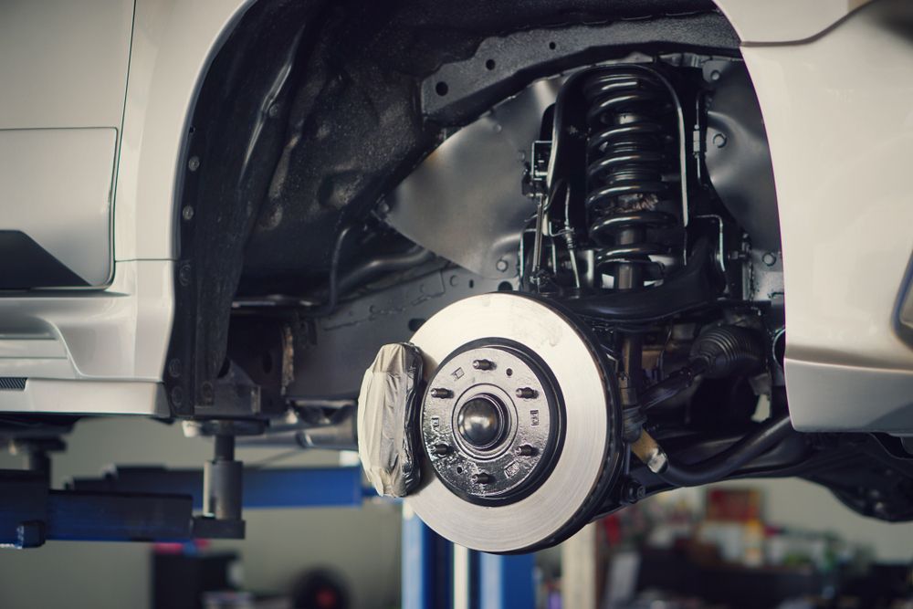 A Car is Being Repaired on a Lift in a Garage — Marx Forster Tyres & Mechanical In Forster, NSW