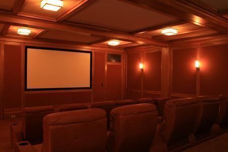 Home theater with brown leather recliners, screen, and warm wood paneling.
