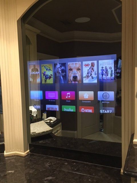A large TV screen displaying a media interface is mounted in an arched doorway.