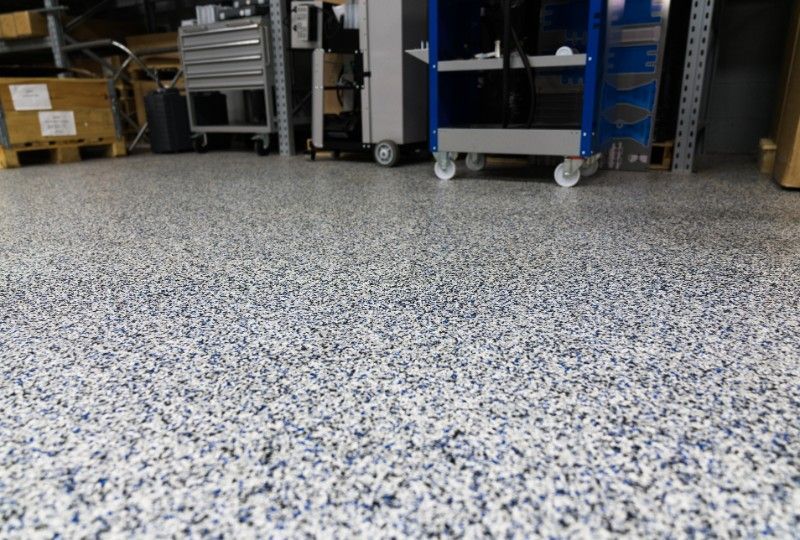 Speckled epoxy warehouse floor with storage carts and boxes in the background
