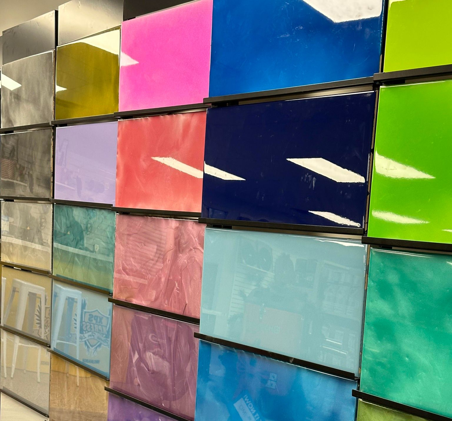 Colorful glossy rectangular panels arranged in a grid, reflecting light in a modern interior.