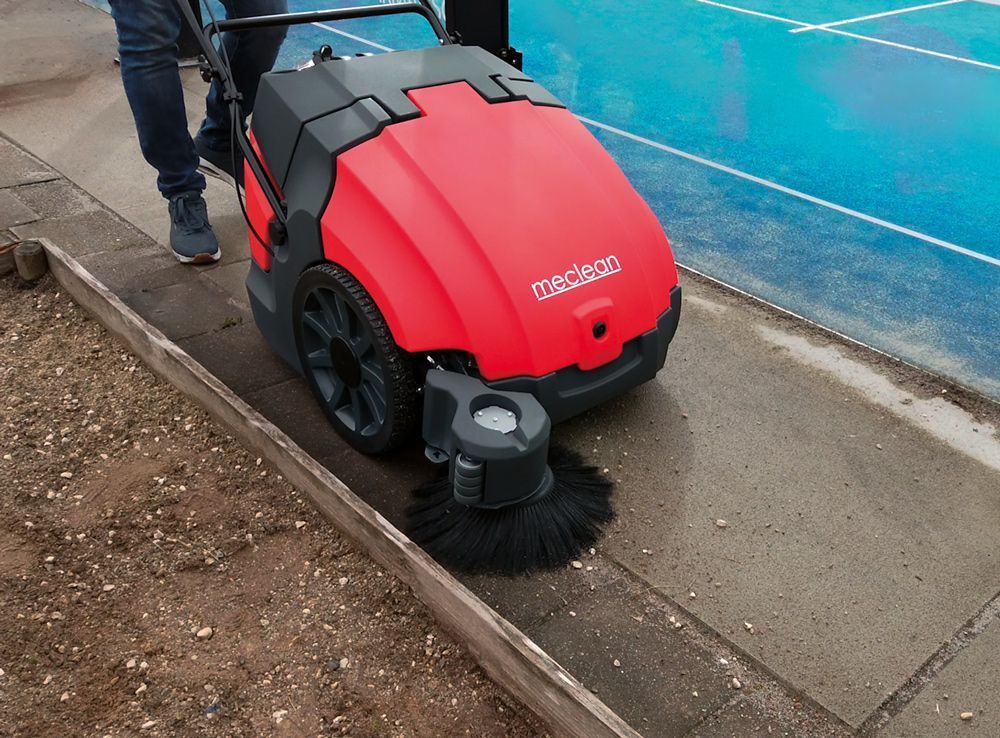 Balayeuse Meclean BUSTER 750 PRO nettoie la dalle béton autour d'un terrain de padel