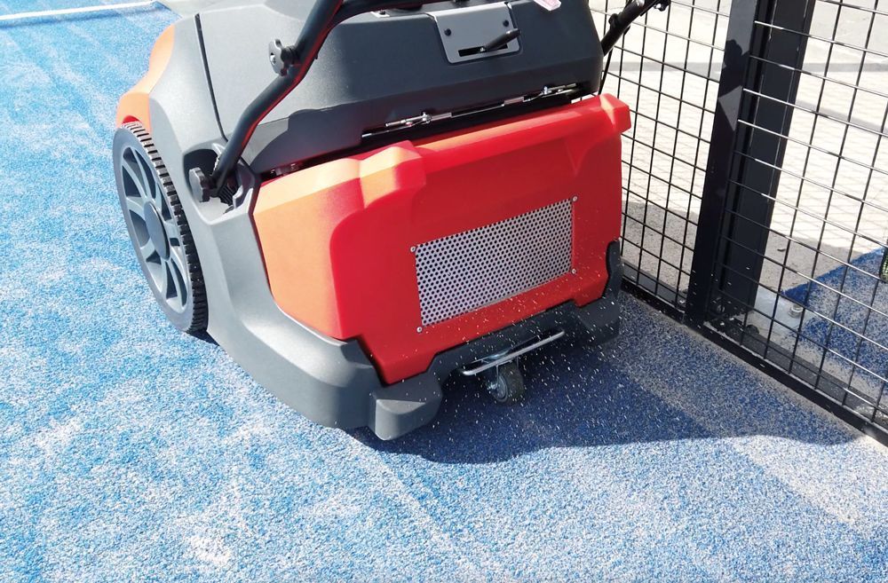 Balayeuse Meclean BUSTER 750 PRO redistribue le sable de remplissage sur terrain de padel bleu