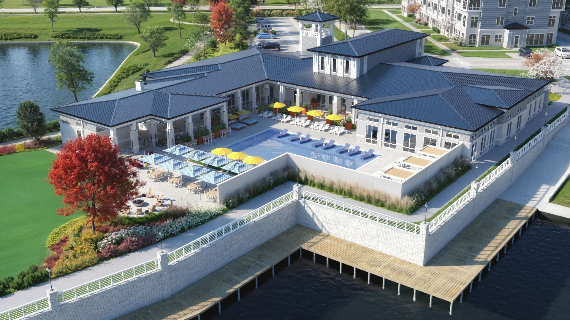 Aerial view of a waterfront resort with a pool, lounge chairs, and surrounding buildings