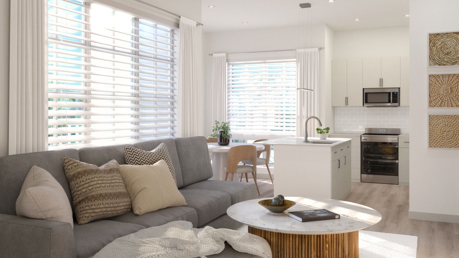 Bright modern living room and kitchen with gray sofa, white walls, large windows, and round coffee table.
