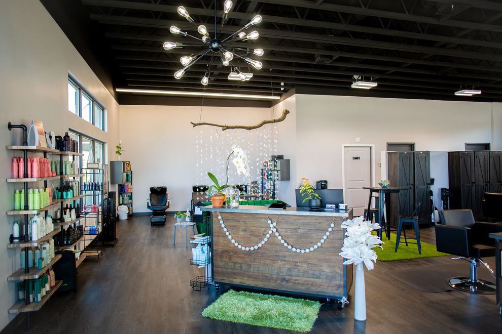 A modern hair salon with product shelves, a front desk adorned with string lights, and a Sputnik-style ceiling light.