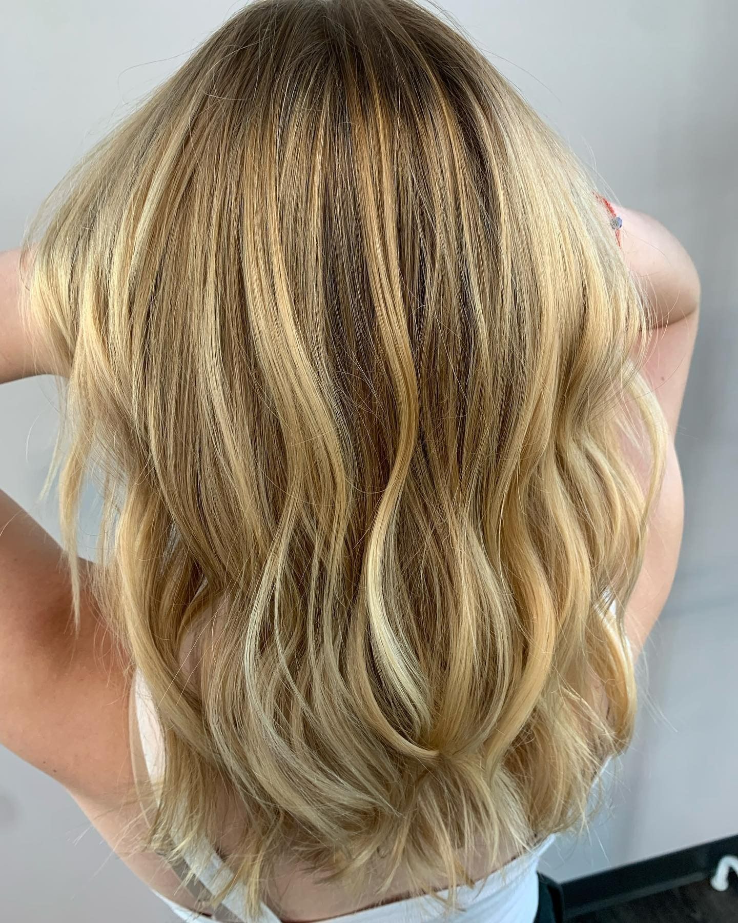 Back view of wavy, blonde hair with texture crimping at the roots, shown against a plain background.