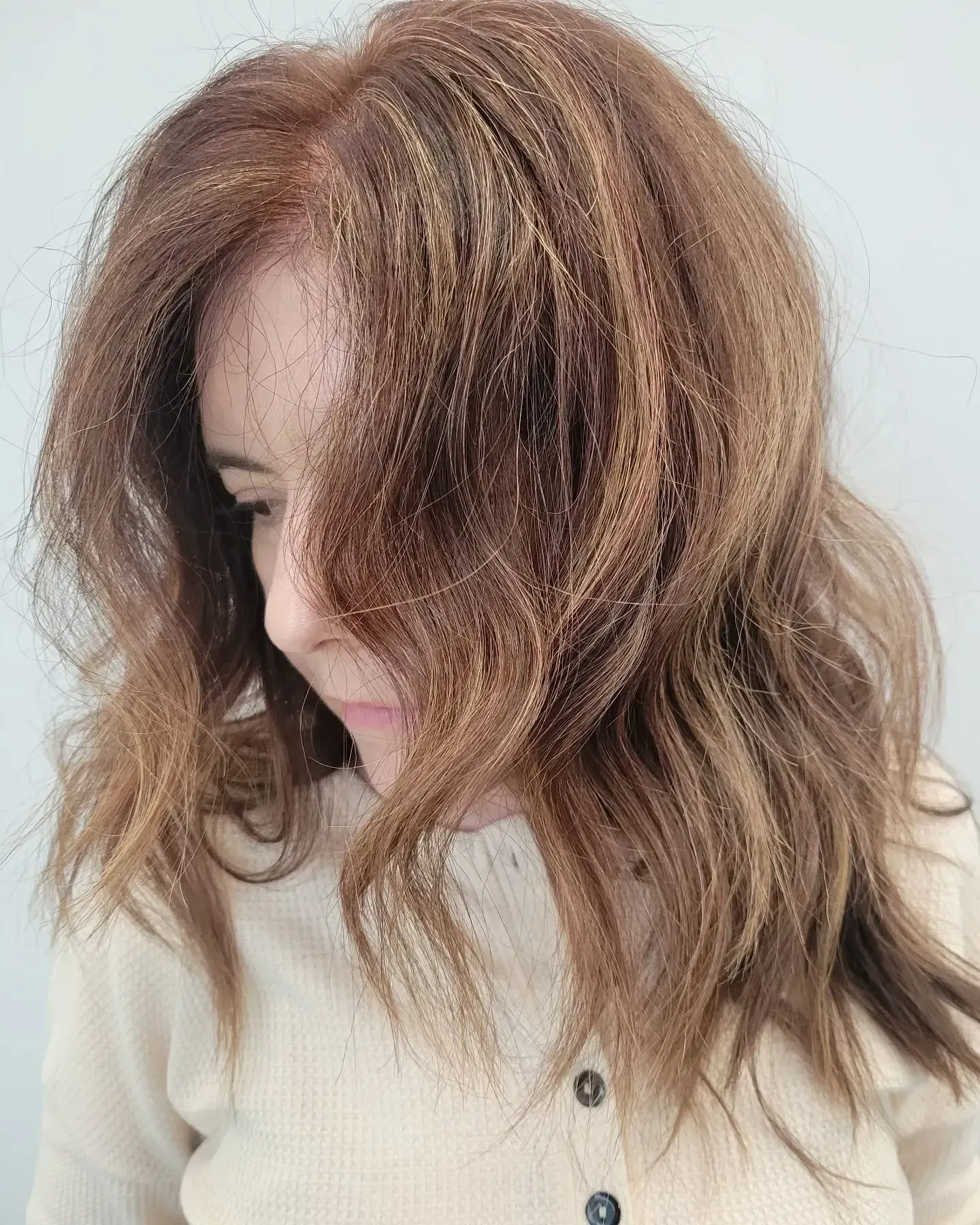 A person with shoulder-length, light brown, wavy hair styled with a crimped texture.