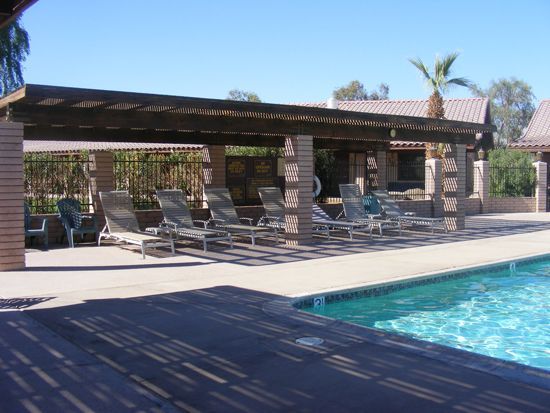 Poolside lounge area with shaded seating, lounge chairs, and a swimming pool.