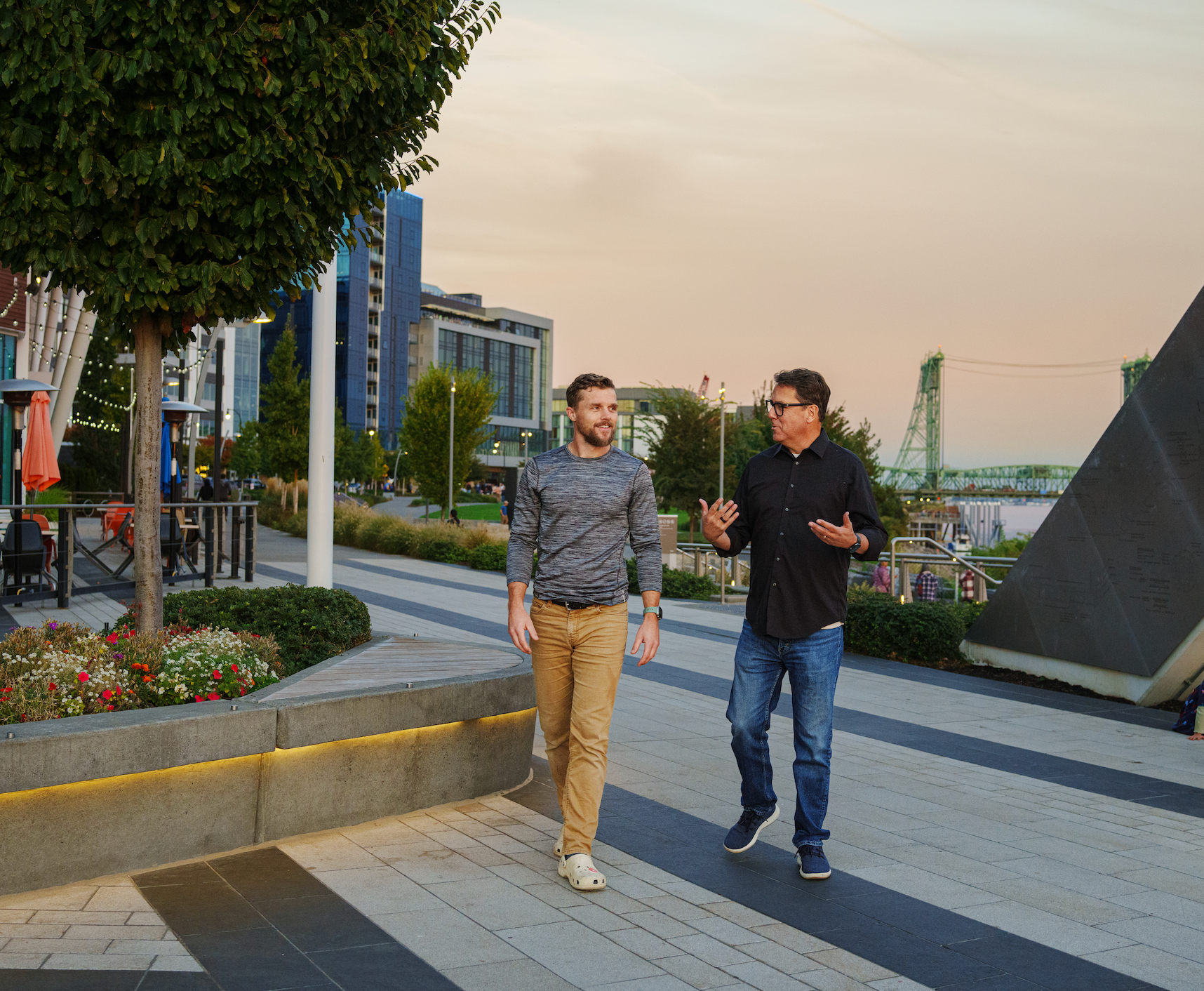Two men are walking down a sidewalk and talking to each other