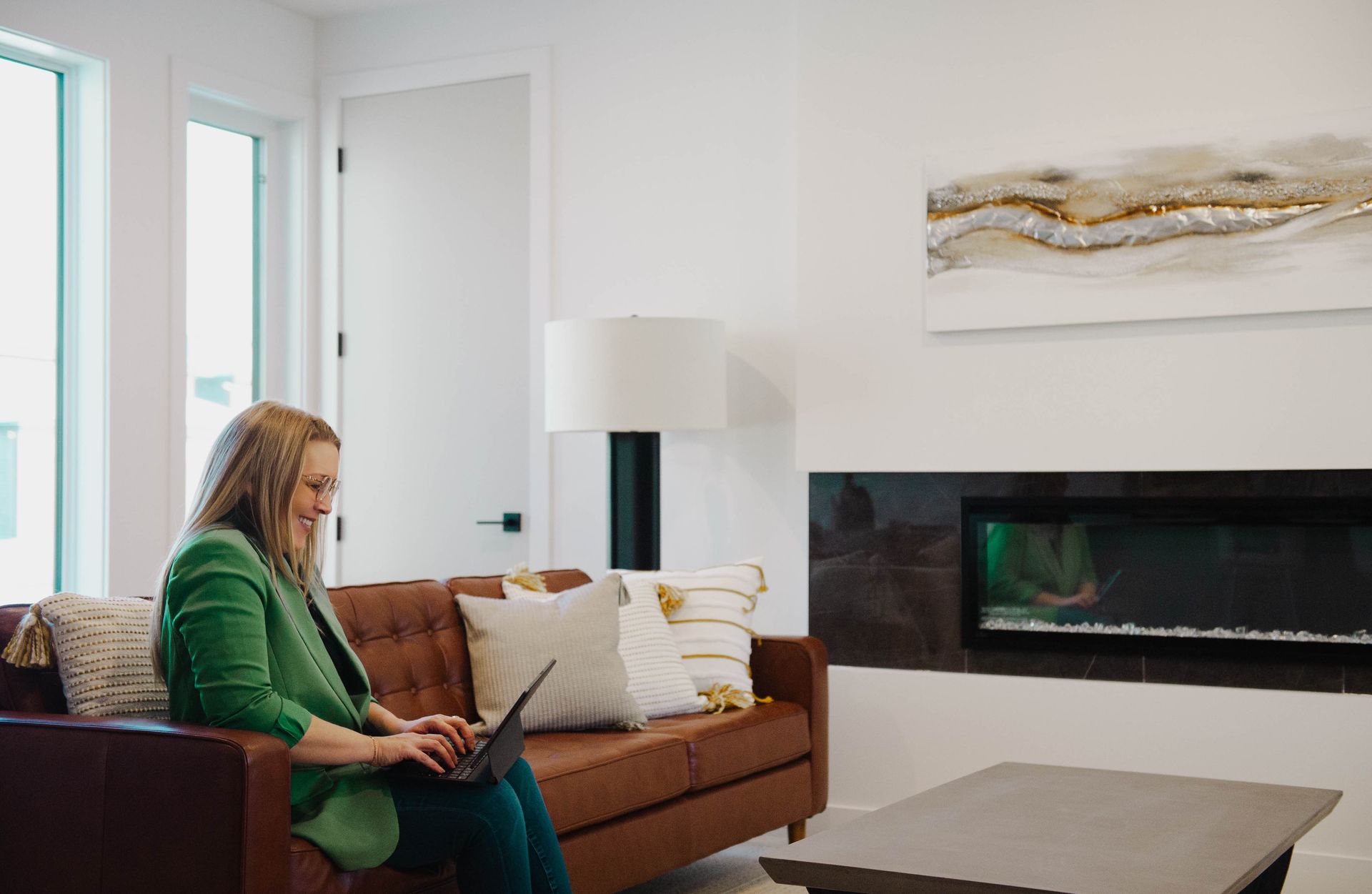 A woman is sitting on a couch using a laptop computer.