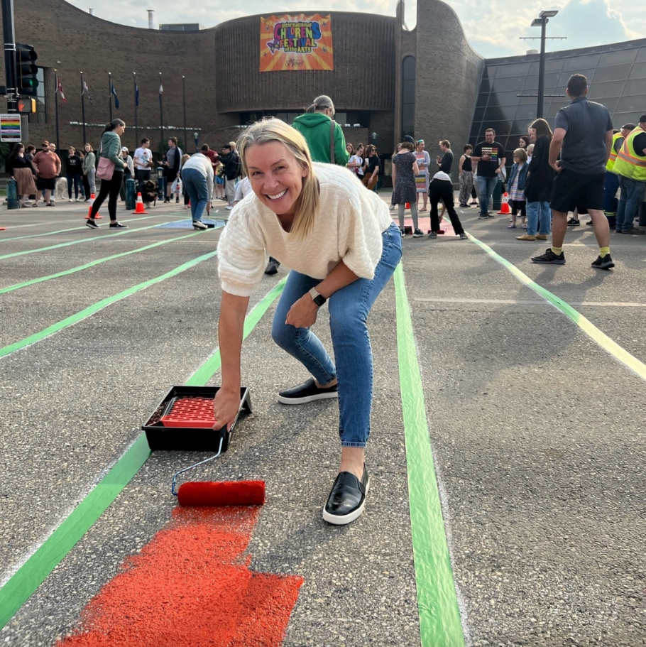 A woman is painting a red arrow on the ground