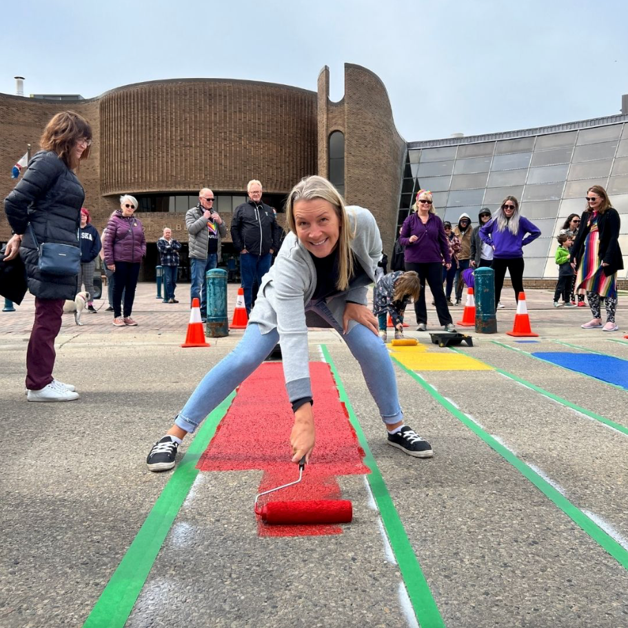 A woman is painting a red carpet with a roller