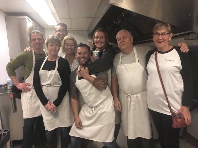 A group of people wearing aprons are posing for a picture in a kitchen.