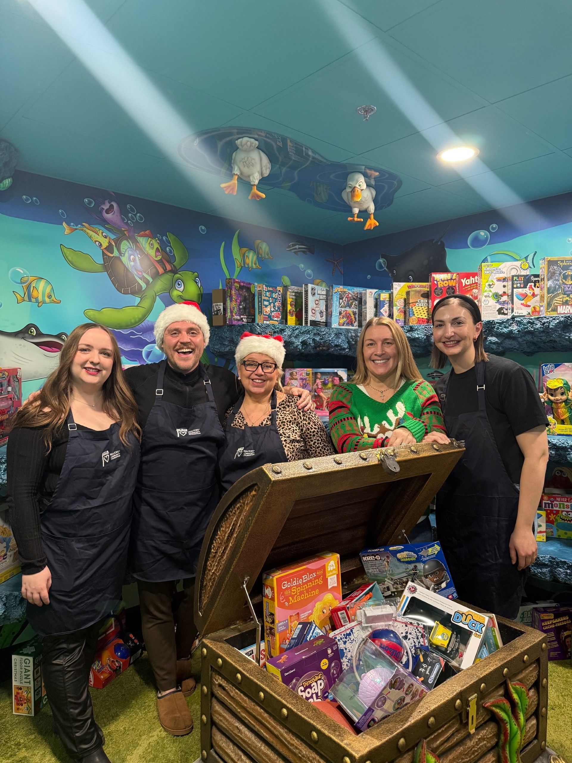 A group of people standing around a treasure chest filled with toys.