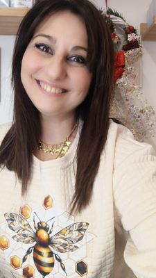 Una donna sorride e indossa un maglione con un'ape sopra.