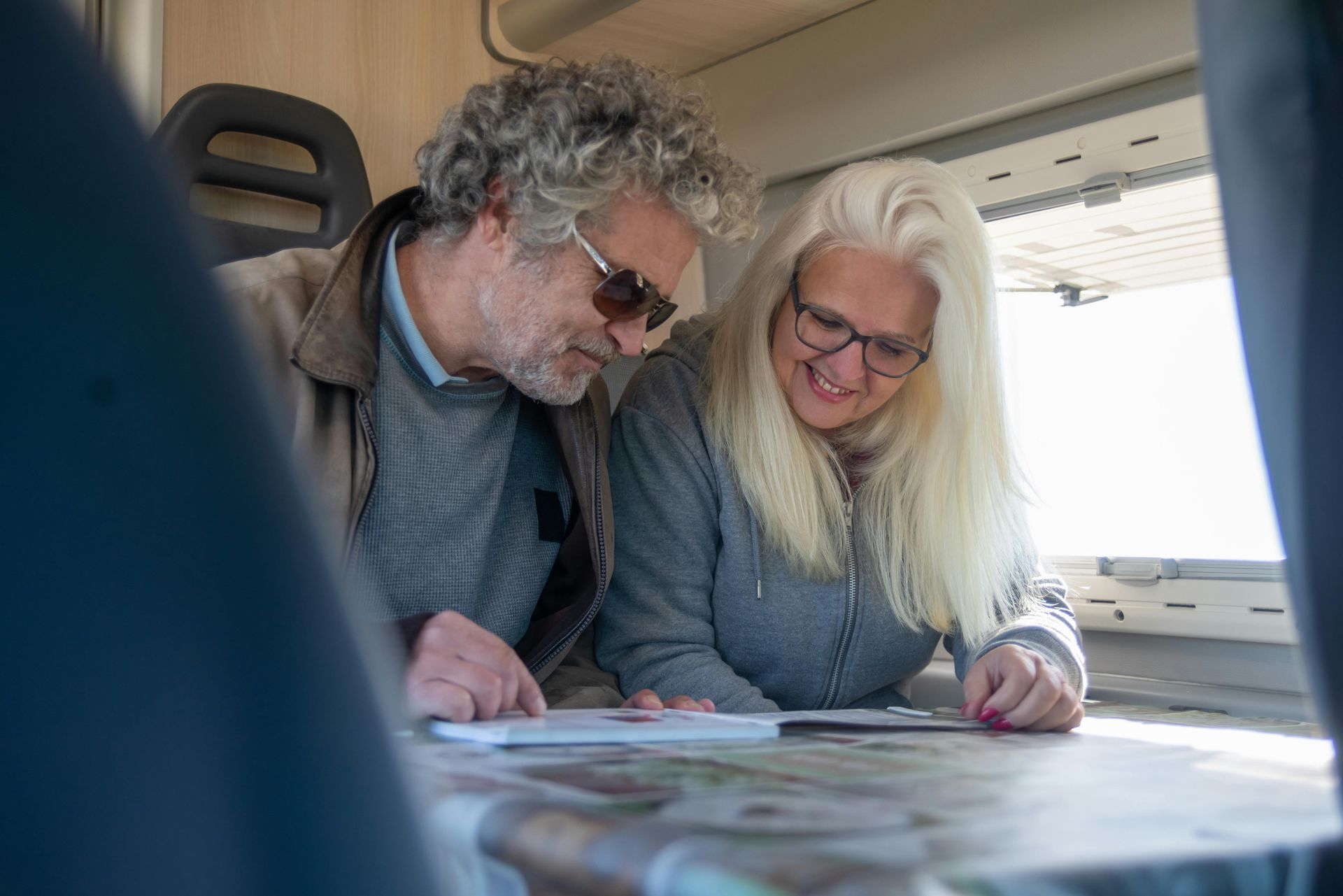 Two people reviewing papers together in a bright train carriage