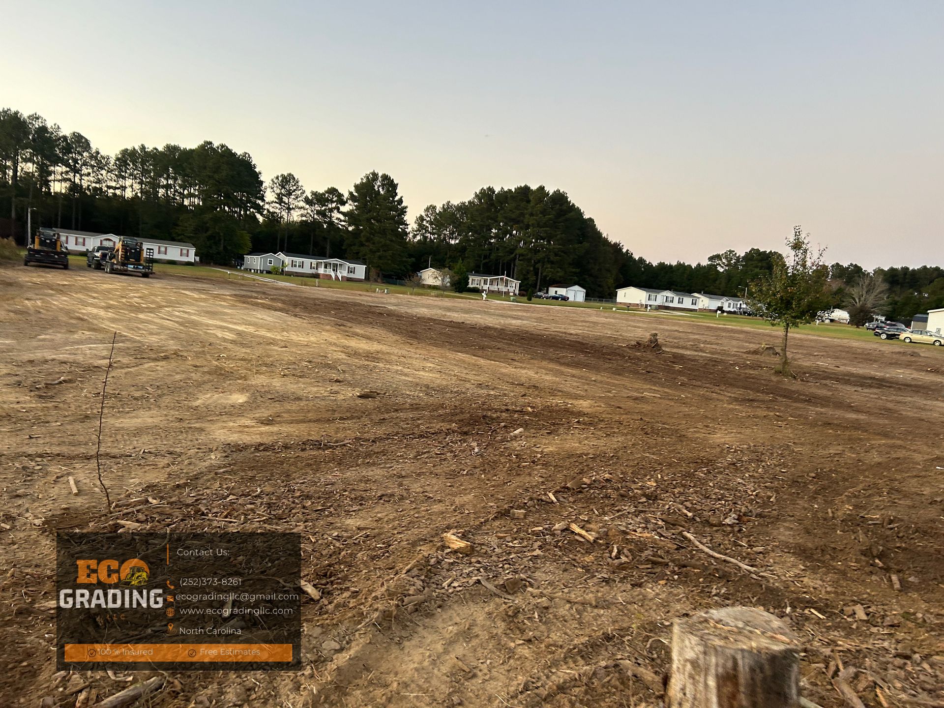 Graded land in front of a line of mobile homes; dusk setting.