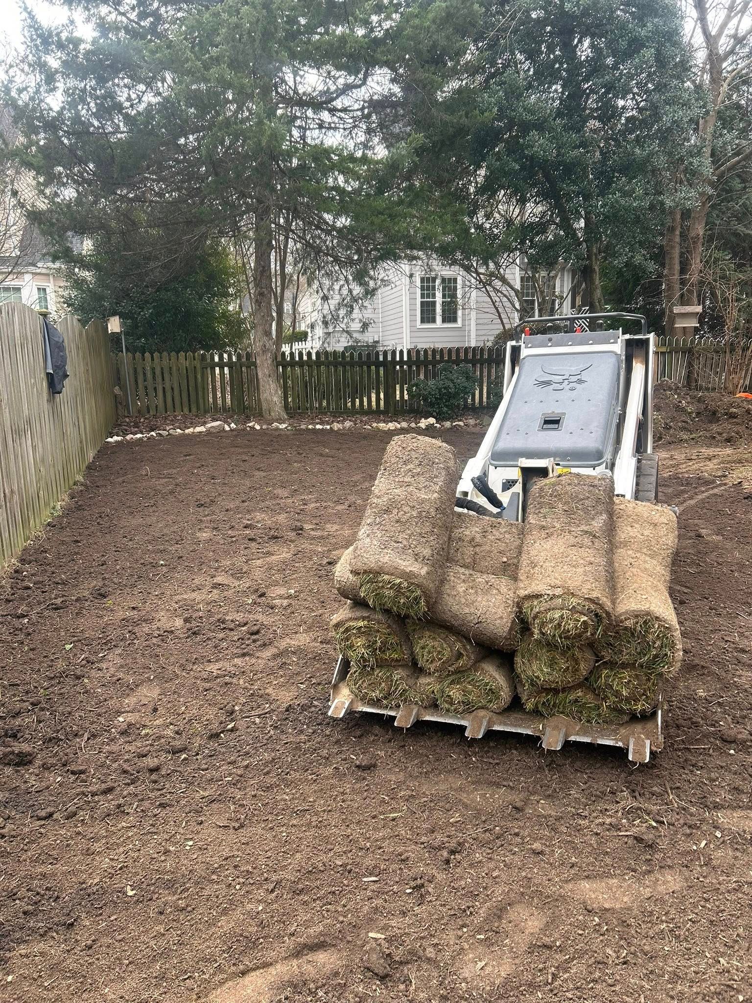 Bobcat holding a pallet of sod in a yard, ready for installation.