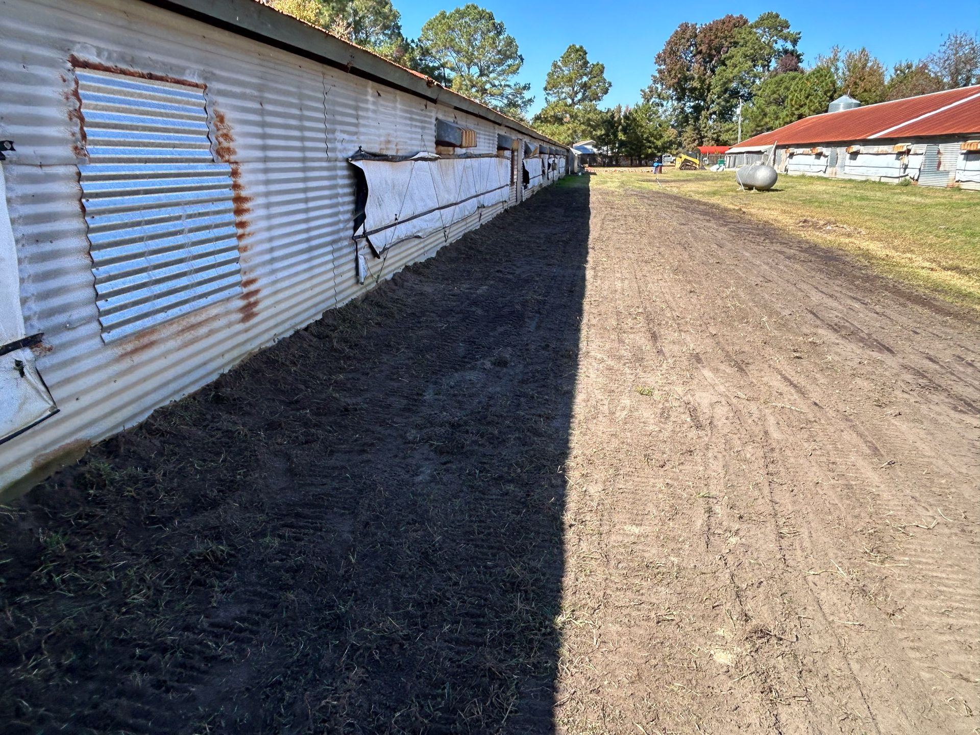 A long, corrugated metal building with a dirt path beside it.