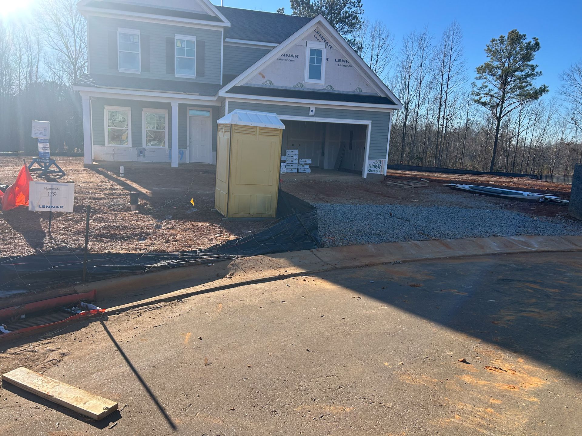 New house under construction with a portable toilet in the yard.