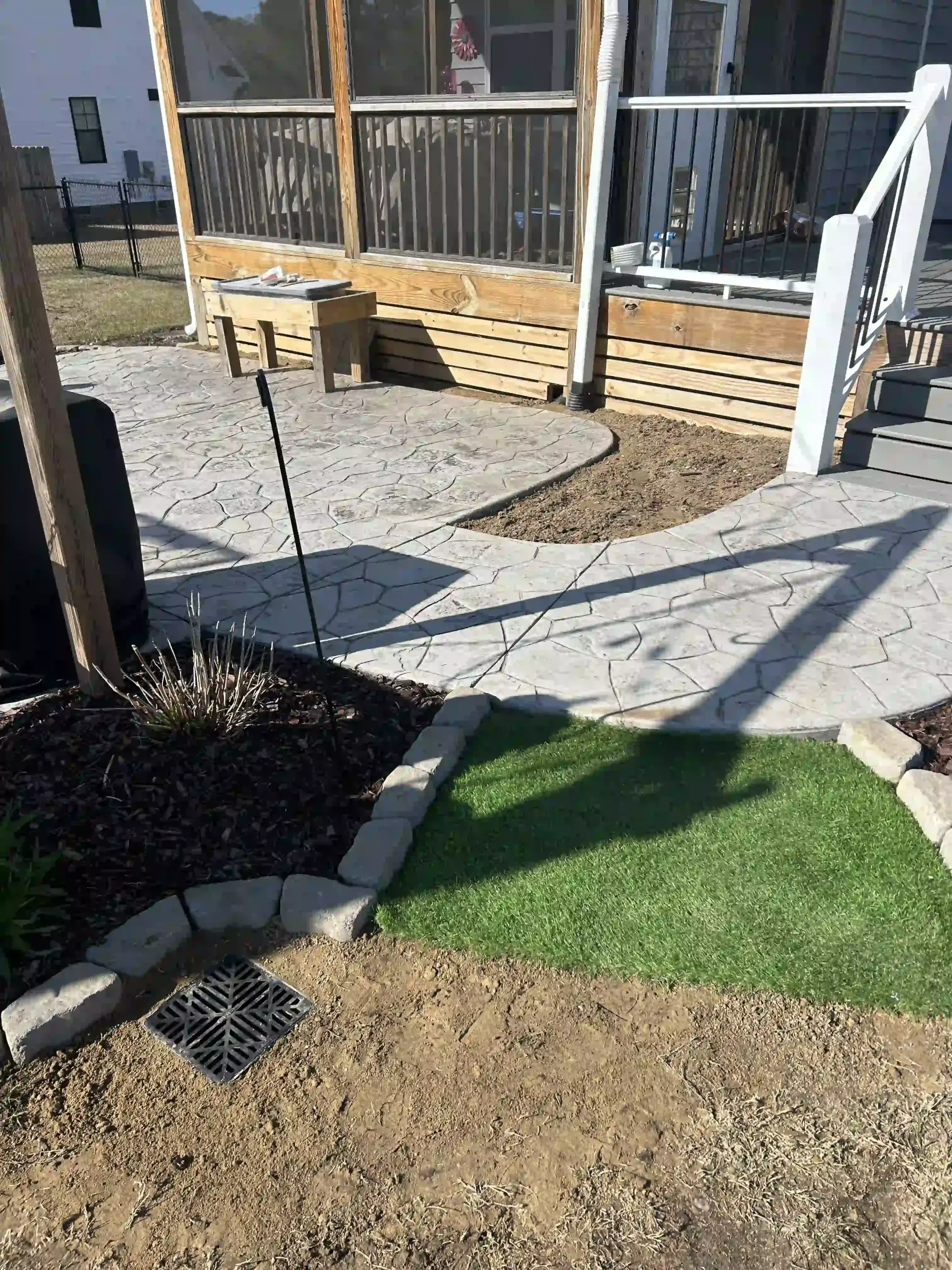 Backyard patio with gravel path, stepping stones, grass patch, and wooden deck railing