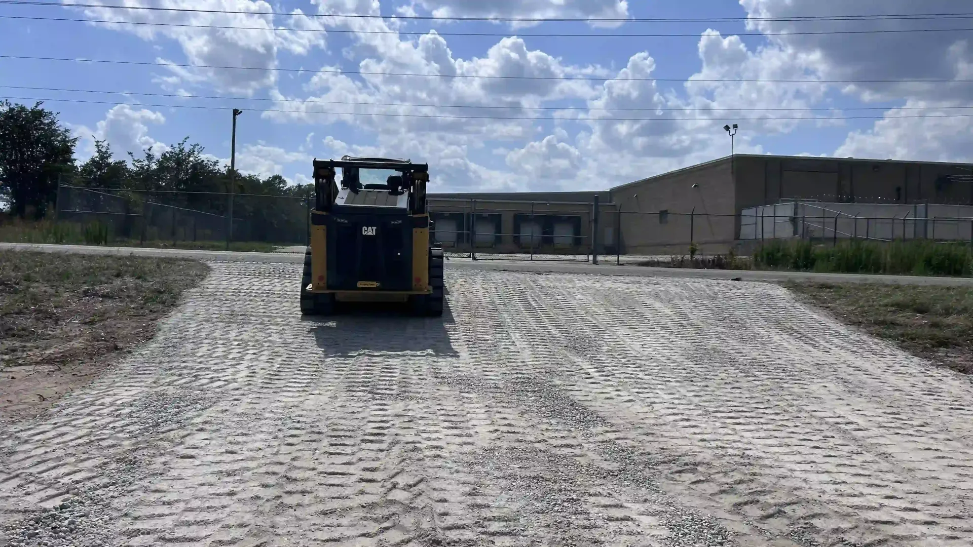 Yellow bulldozer on a dirt slope at a construction site under a partly cloudy sky