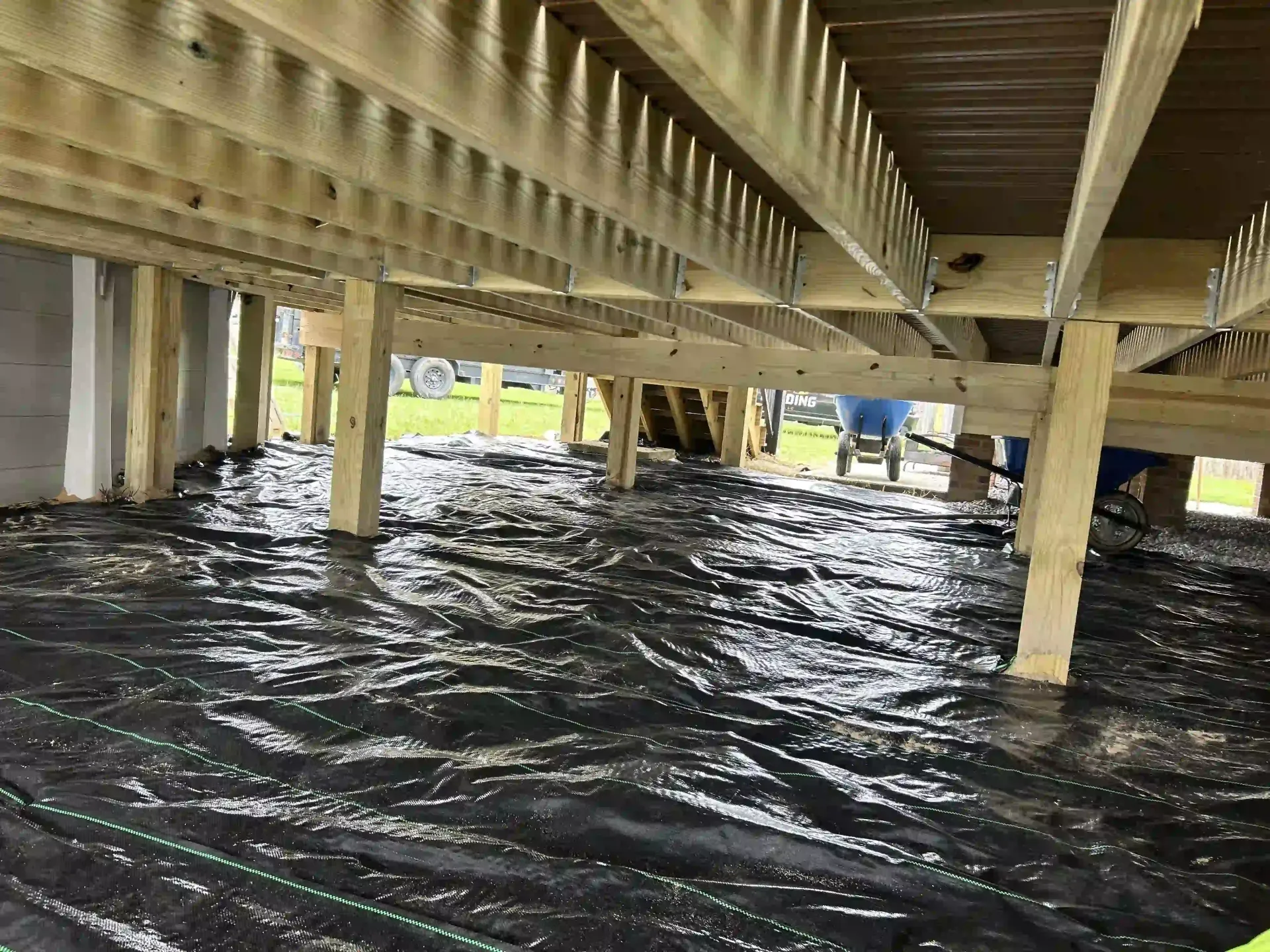 Floodwaters under a wooden bridge with a few people standing in the distance