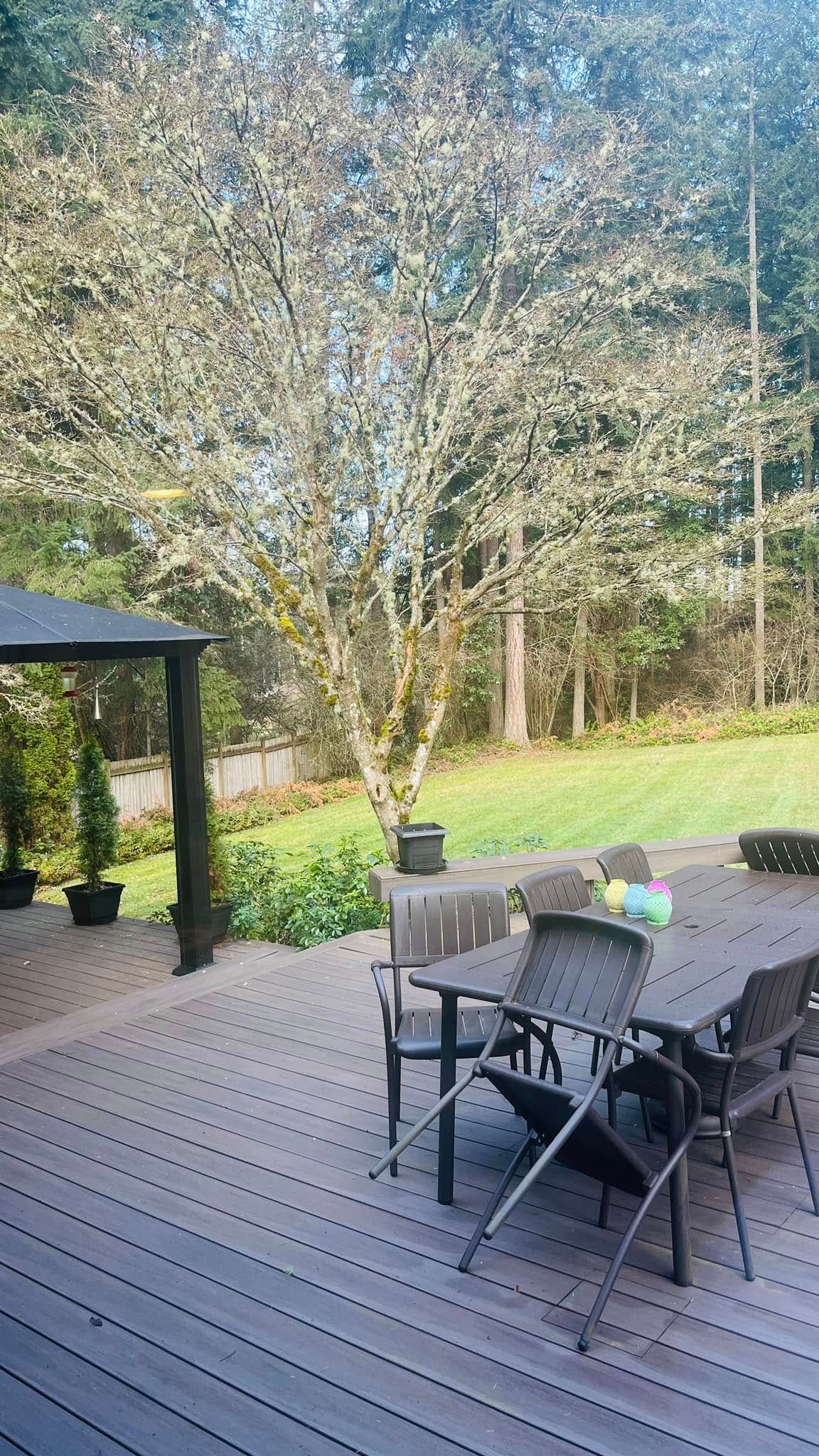 A wooden deck with a table and chairs and a gazebo in the background.