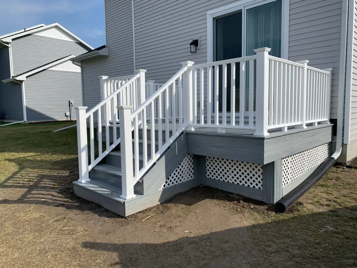 White deck with gray skirting and stairs, attached to a light-colored house.