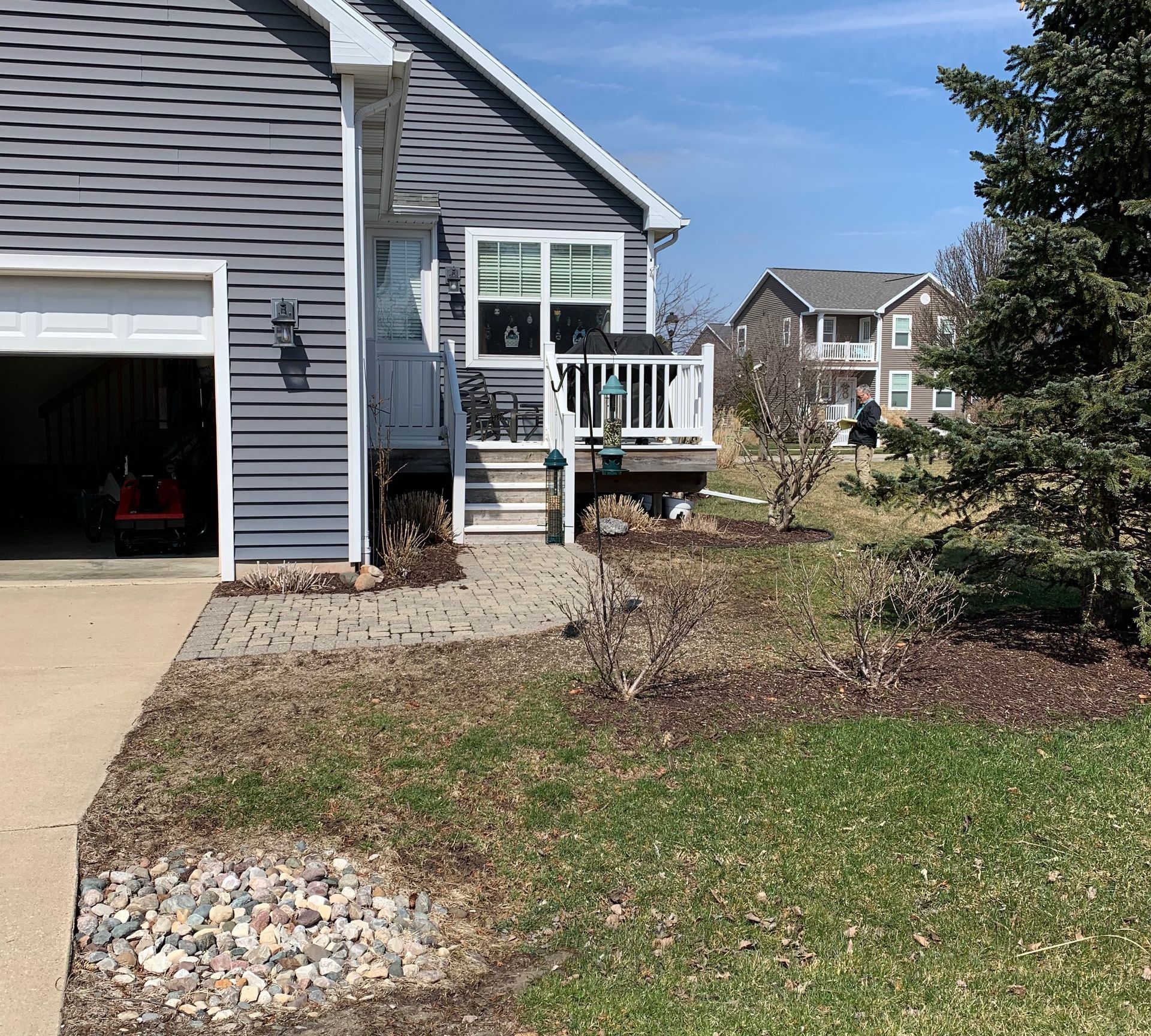 House exterior with garage, front steps, and landscaped yard on a sunny day.
