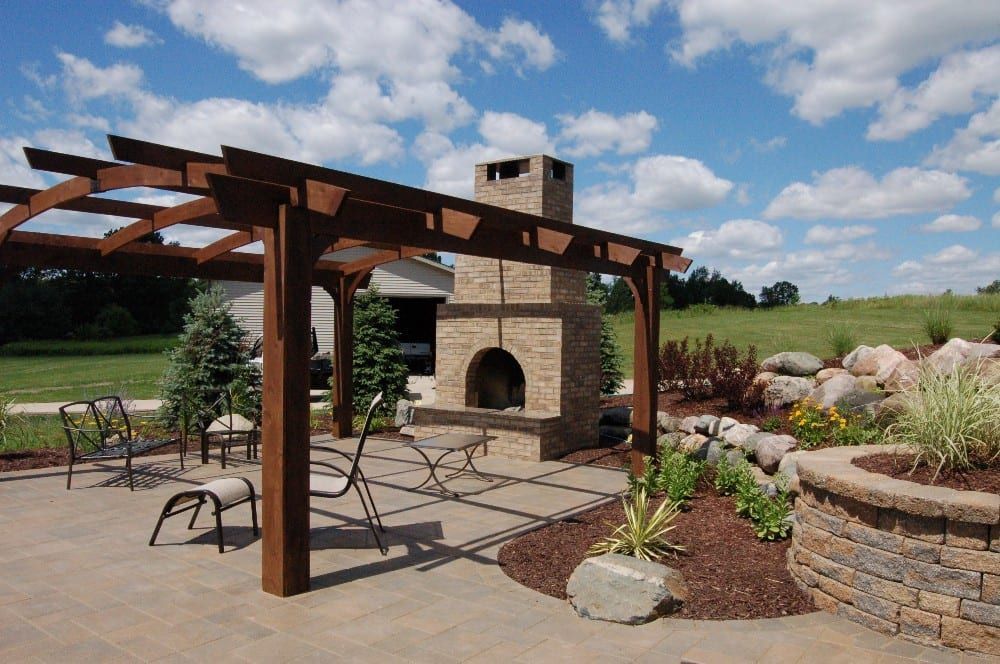Outdoor patio with pergola, fireplace, and seating on a sunny day.