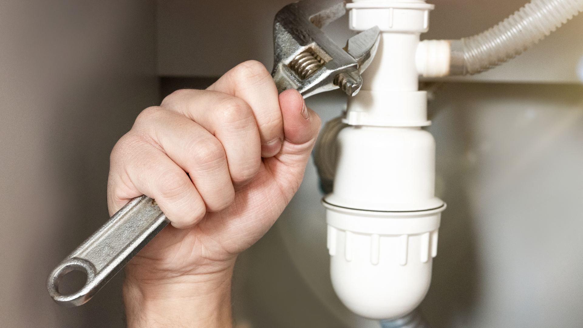 A hand holds a clear glass under a chrome kitchen faucet as water pours into the glass.