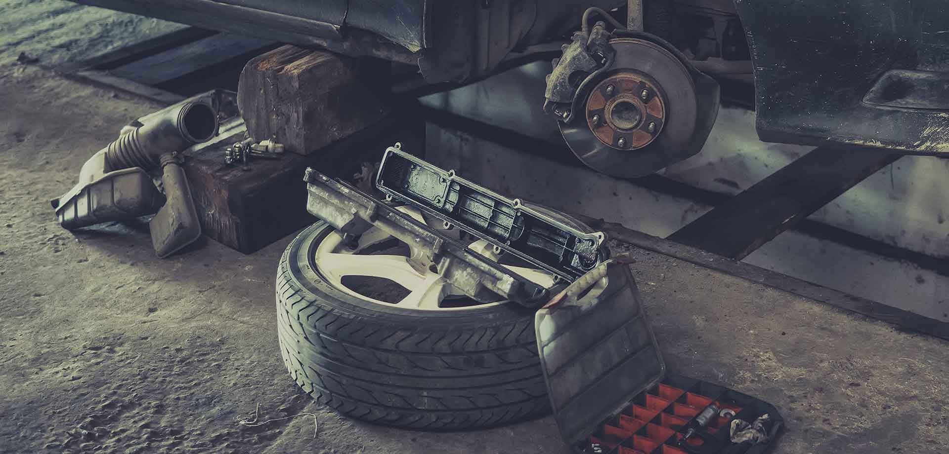 A tire is sitting on the ground next to a car in a garage.