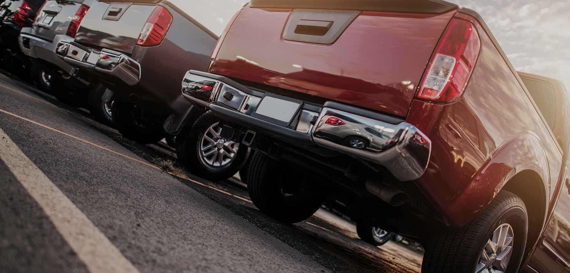 A row of pickup trucks are parked in a parking lot.