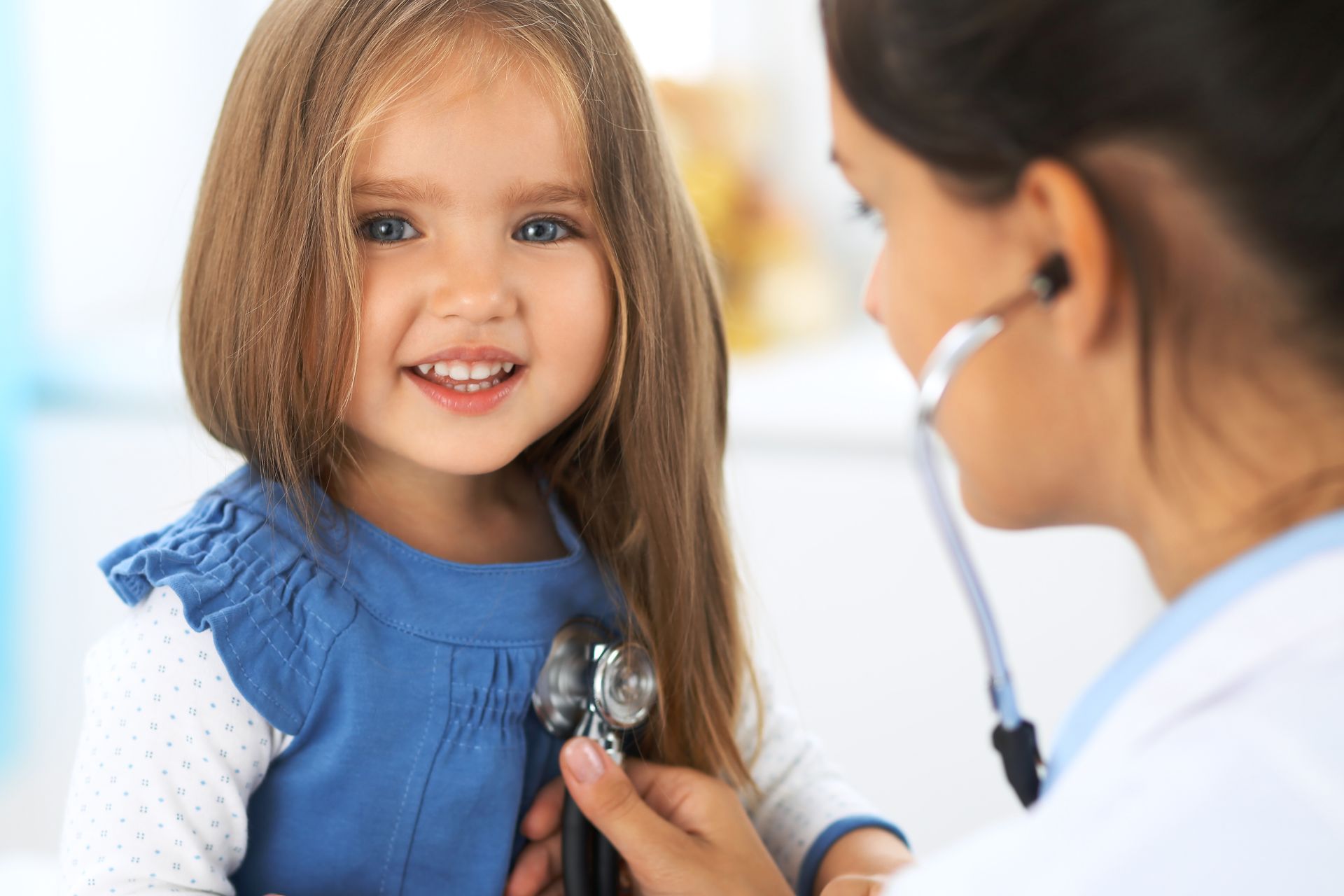 A little girl is being examined by a doctor with a stethoscope.