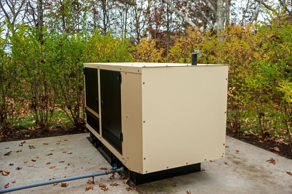 A generator is sitting on a concrete surface in the woods. A generator is sitting on a concrete surface in the woods.