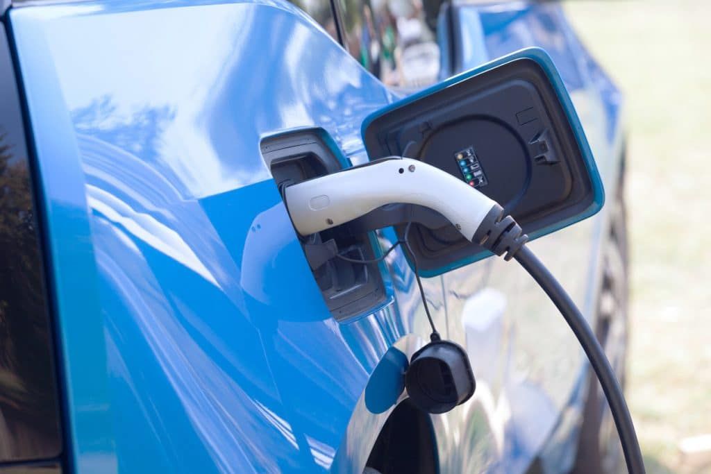 A blue electric car is being charged at a charging station. A blue electric car is being charged at a charging station.