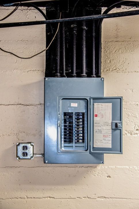 A close up of an electrical box on a wall with the door open. A close up of an electrical box on a wall with the door open.