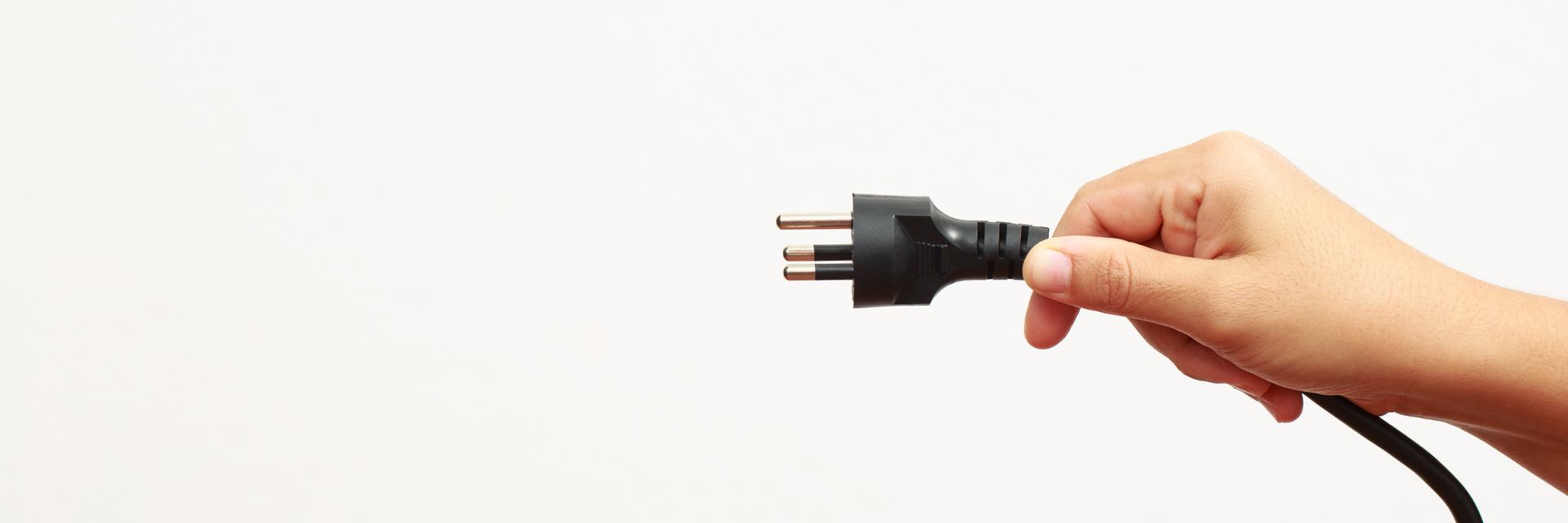 Hand holding a black electrical plug against a white background. Hand holding a black electrical plug against a white background.
