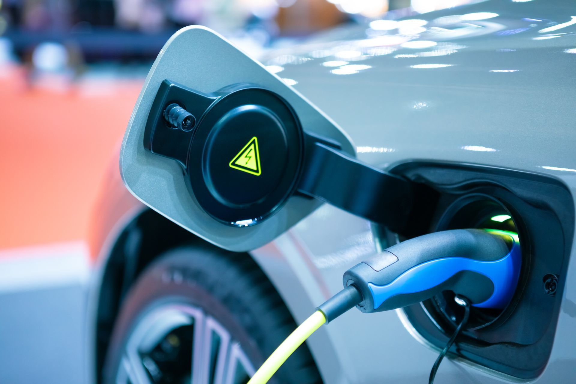 Electric car charging, charging port open, cable plugged in.