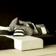 Modern black-and-white sectional sofa with patterned pillows and a white chaise lounge