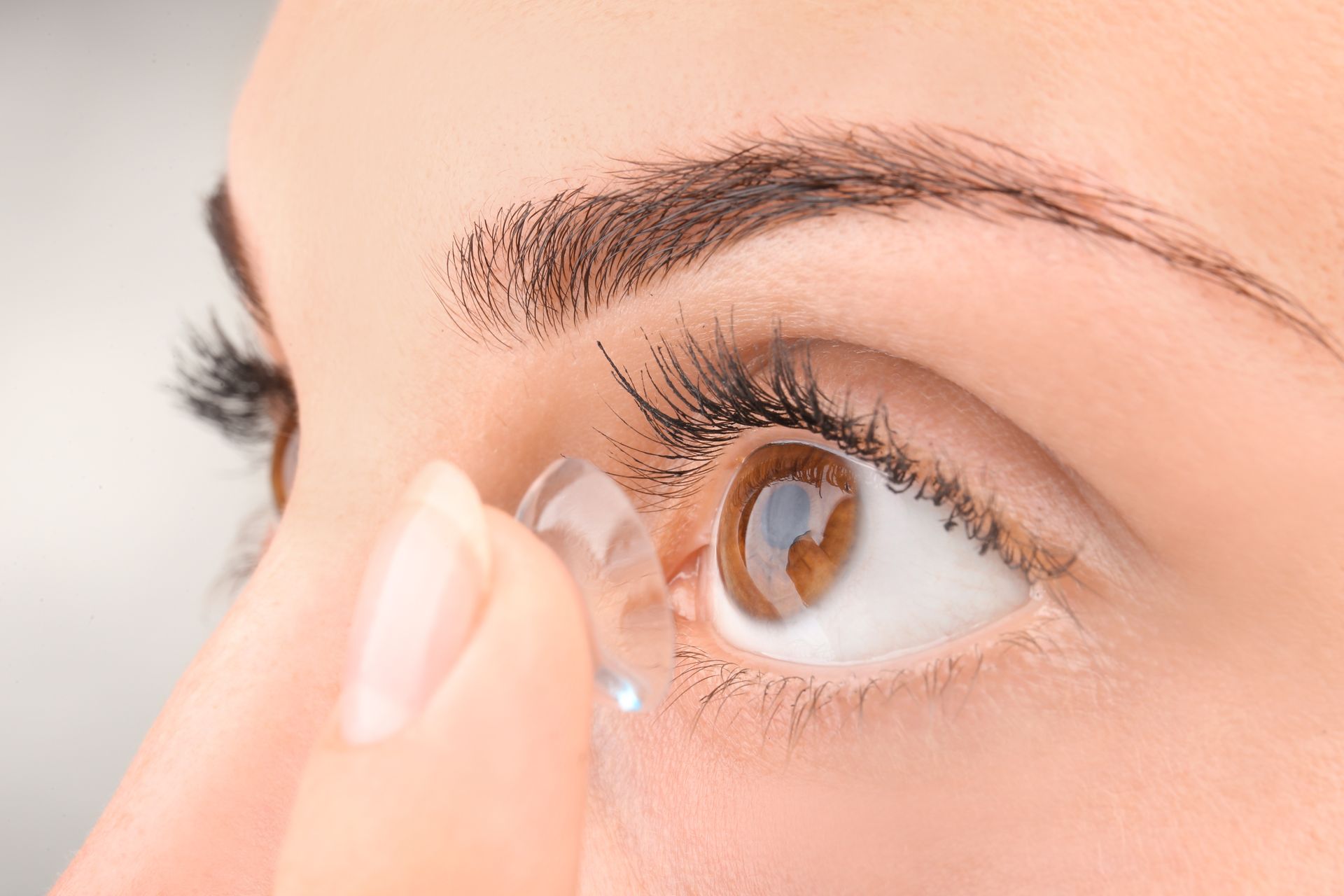 Close-up of a person inserting a contact lens into an eye Close-up of a person inserting a contact lens into an eye