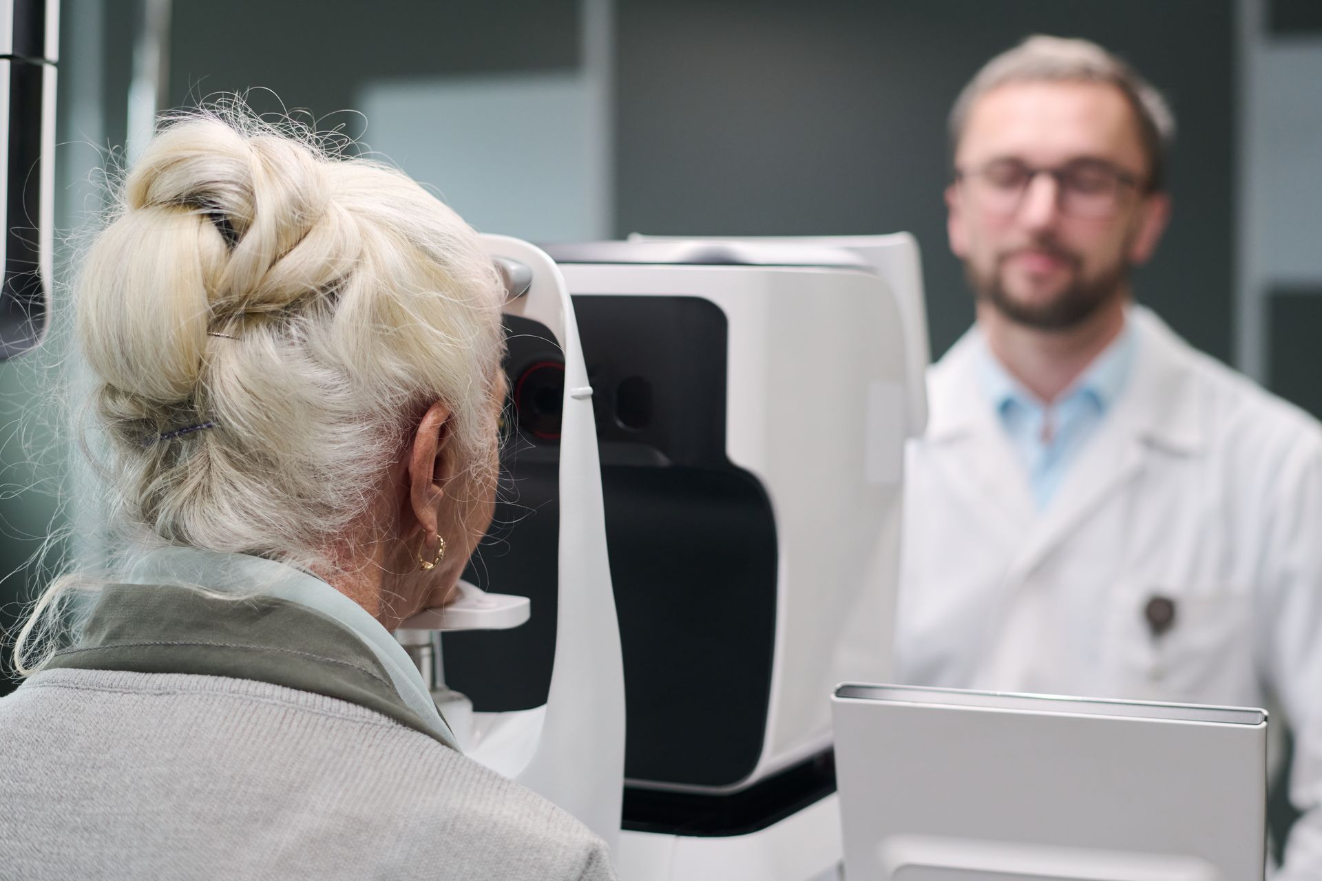Woman looking into a medical imaging device while a clinician stands nearby in a clinic.