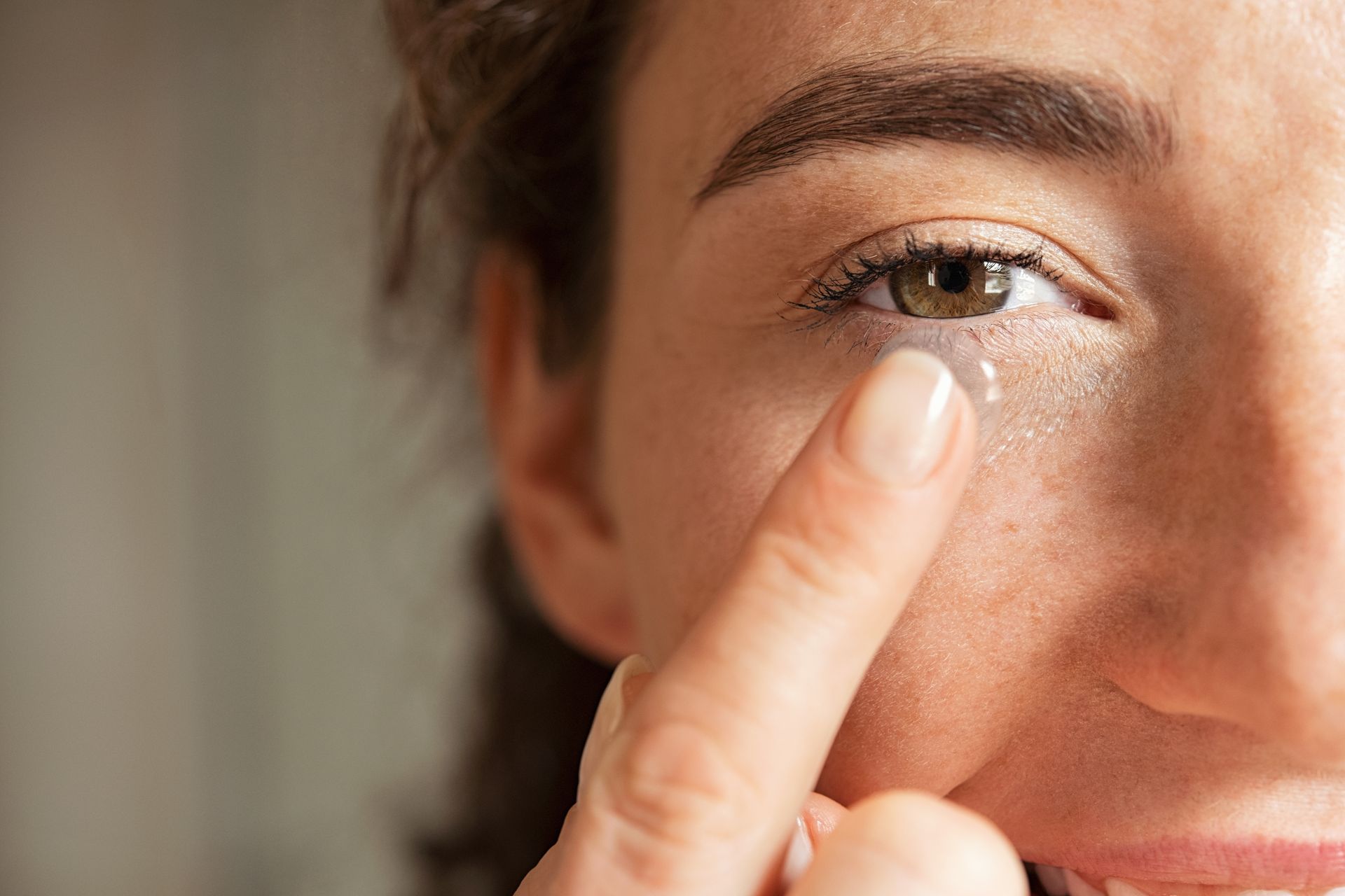 Close-up of a person applying cream under one eye with a fingertip. Close-up of a person applying cream under one eye with a fingertip.