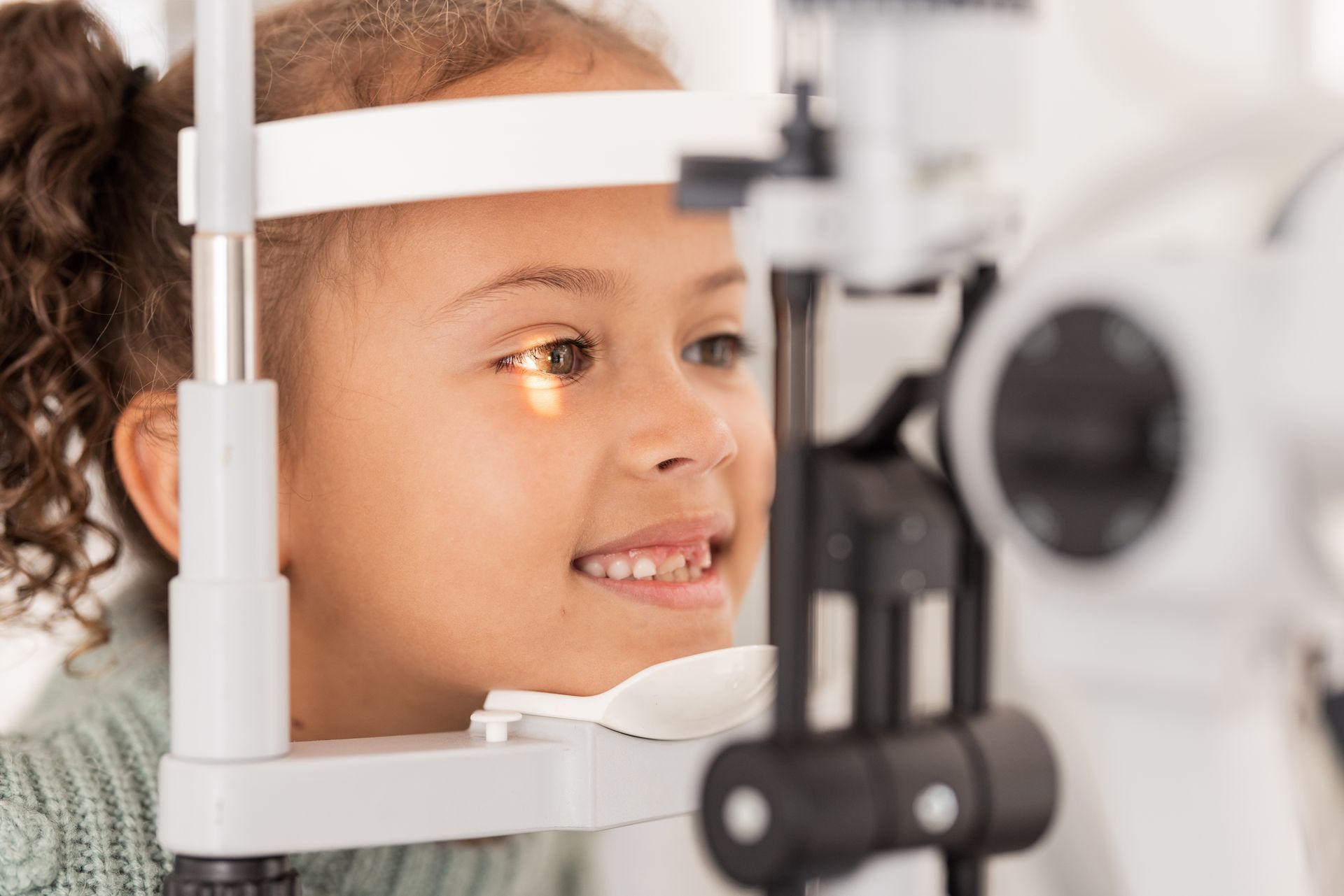 Child smiling during an eye exam with an optometrist machine